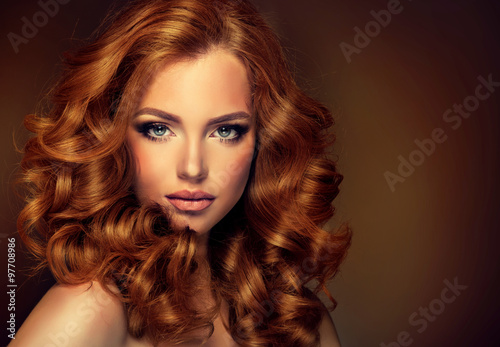 Girl model with long red wavy hair. Big curls on the red head . Hairstyle permanent waving