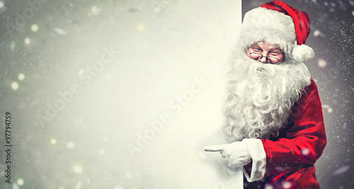 Smiling Santa Claus pointing on blank advertisement banner background with copy space