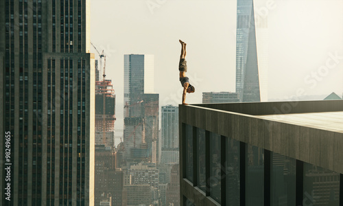 Man performs a handstand on the edge of a skyscraper