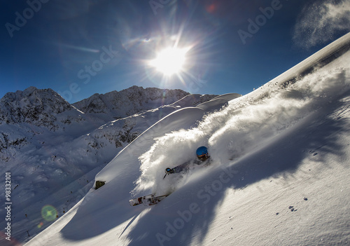 A freeride skier make a turn in powder snow on a sunny day in western Austria