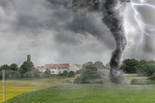 Black tornado funnel and lightning over field during thunderstorm