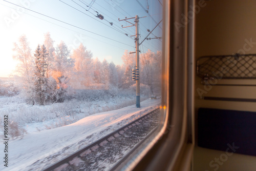 pink sunrise in winter forest through the window of the train