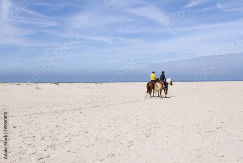Two people on horses on the beach at the North Sea in Norderney, Germany