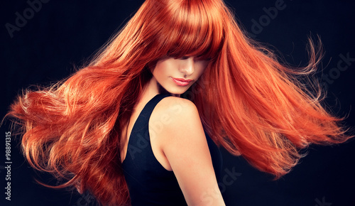 Beautiful model girl with long red curly hair . Hairstyle and cosmetics