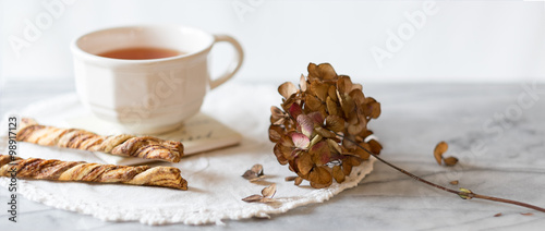 Cup of tea and cinnamon twist cookies with dried hydrangea flower 