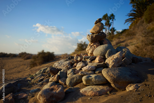 Sterty kamieni na pustyni / Piaszczyste i kamieniste wydmy ze stylowymi formami na szerokiej pustyni pod niebieskim niebem
