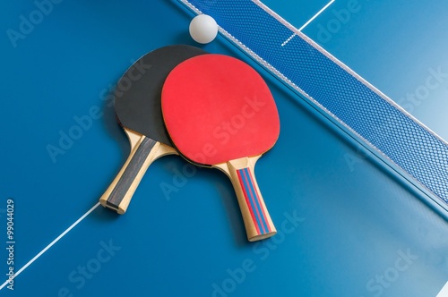 Ping pong rackets and table tennis net on wooden table