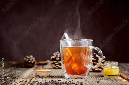 Steaming tea and honey on a wooden table