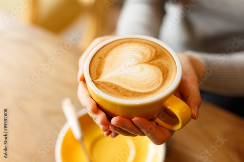 lady's hands holding cup with sth heart-shaped
