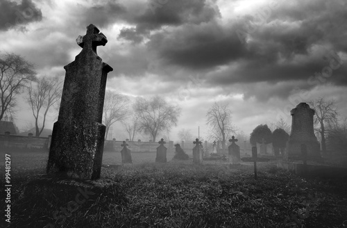 Old creepy graveyard on stormy winter day in black and white