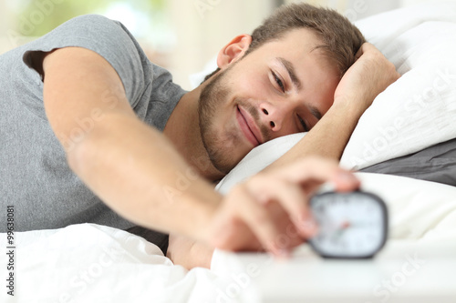 Happy wake up of a happy man stopping alarm clock