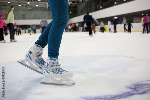Feet skater in motion on the ice rink with many people. Figure skates