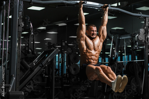 Athlete muscular fitness male model pulling up on horizontal bar