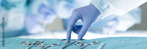 Close-up of scrub nurse taking medical instruments