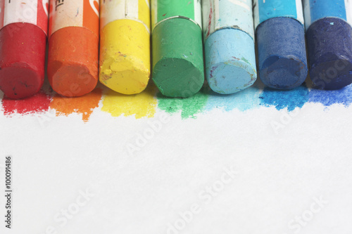 Set pastel art on a white background. Colors of rainbow. Pastel pencils are located along the upper side of the frame