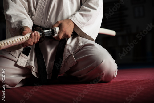 Close uo of young martial arts fighter with katana siting in seiza position