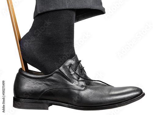 man dons black shoe with shoehorn isolated
