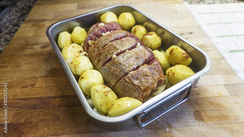 Raw meat loaf and potatoes on wooden background