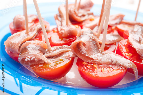 skewers of cherry tomatoes with anchovies on blue dish