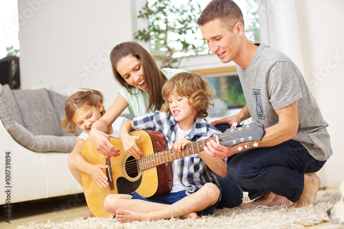 Eltern und Kinder machen Musik mit Gitarre