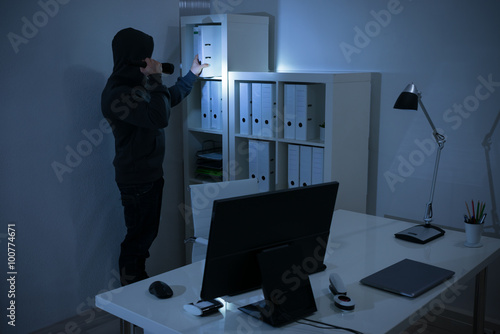 Robber With Flashlight Searching For Documents In Office