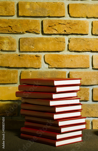 Książki w skórzanej oprawie na tle ściany z cegły.