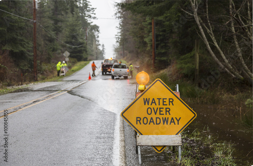 Emergency workers placing warning signs on flooded road