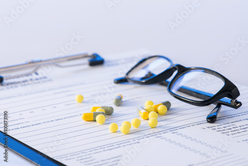 Pills and glasses on top of hospital form. 