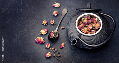 Green tea with flowers roses in cast-iron kettle. Asian style