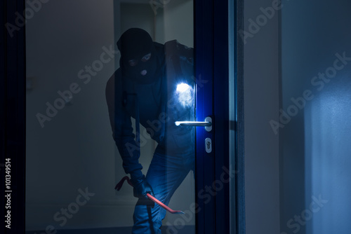 Thief With Flashlight Trying To Break Door