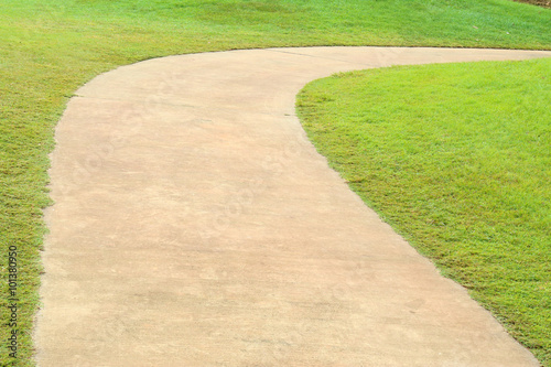 Path curving through green grass in golf course.