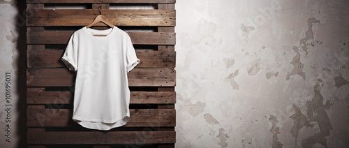 Photo white tshirt hanging in front of concrete wall. Wide