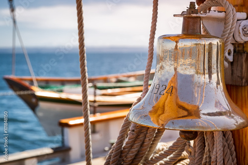 Brass ship bell on a classic big wooden sailboat at sea. Close up