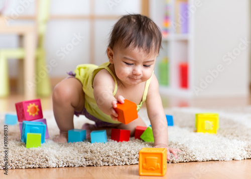 baby toddler playing wooden toys at home or nursery