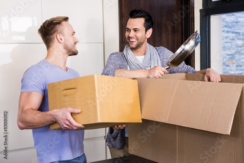 Smiling gay couple unpacking cardboard