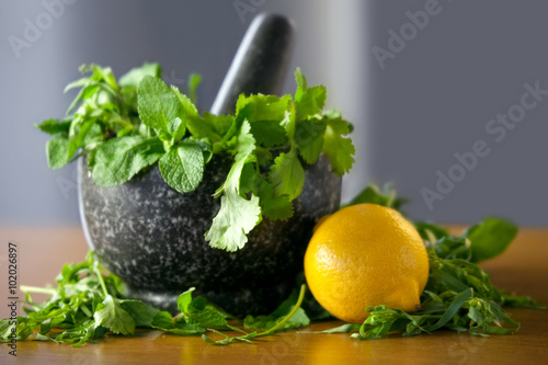 Herb leaf selection in a granite mortar with pestle with lemon