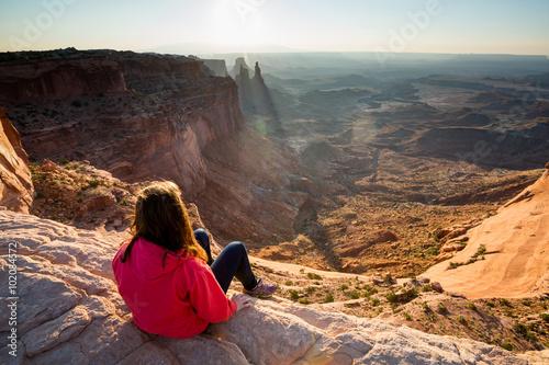 Girl sitting at the Mesa Arch at sunrise, Canyonlands