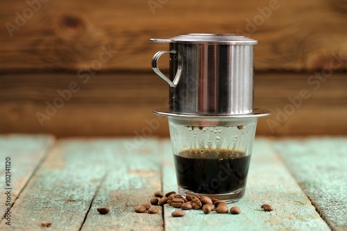 Vietnamese black coffee brewed in French drip filter on turquois