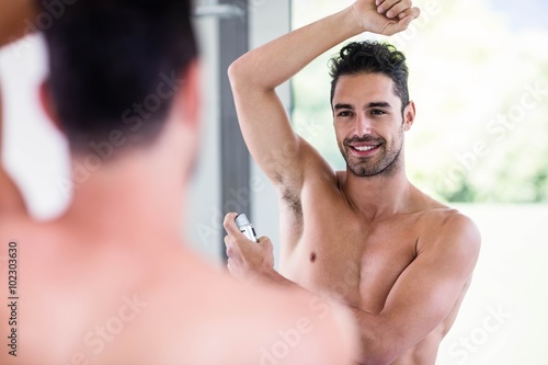 Handsome shirtless man putting deodorant