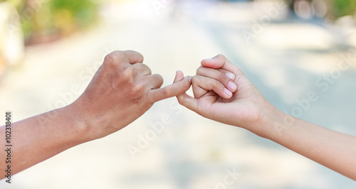 Parent and child hooking their fingers to make a promise