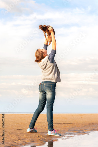 Young cheerful teenage girl holding high up her lovely little To