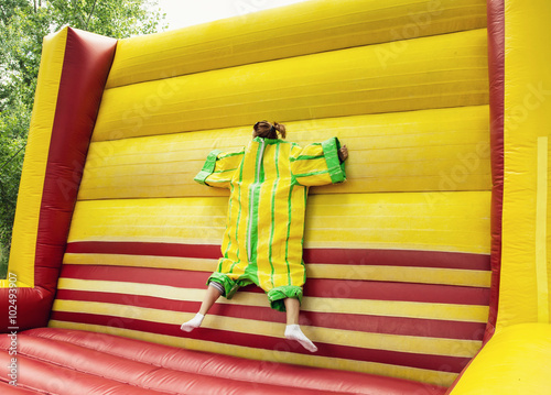 Young woman in plastic dress in a bouncy castle imitates the fly