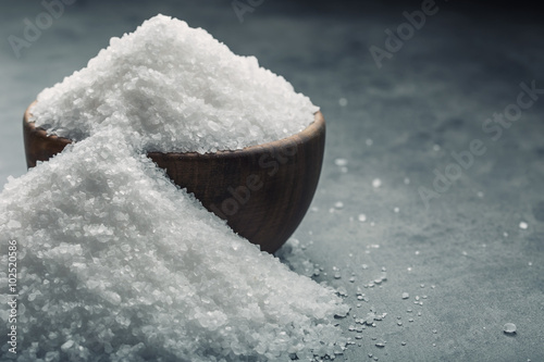 Salt. Coarse grained sea salt on granite - concrete stone background with vintage spoon and wooden bowl.