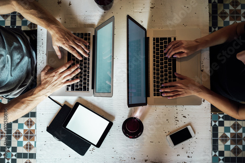 top view of a young woman and a young man who works with a laptops. phone and tablet on the table. digital tablet with blank copy space screen for your information