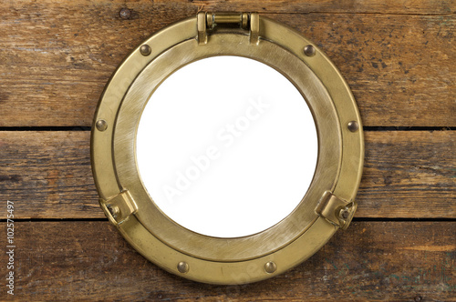 Vintage brass porthole in wooden wall isolated with clipping path