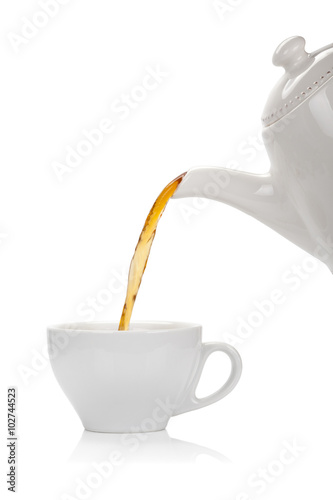 Pouring tea into a cup isolated on white