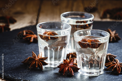 Homemade anise liqueur in a glass on a dark background, selectiv