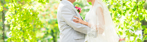 wedding couple hugging, the bride holding a bouquet of flowers in her hand, the groom embracing her