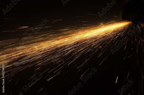 Glowing flow of steel metal spark particles shine in the dark background