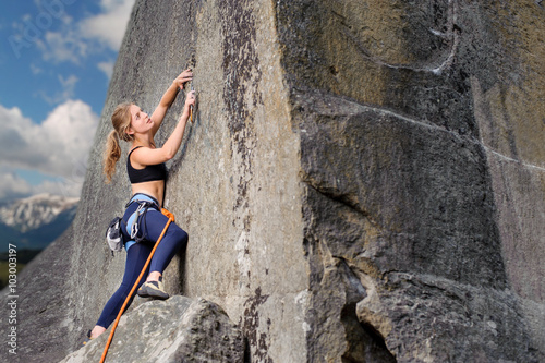 Young athletic girl climber lead climbing and clipping carbines